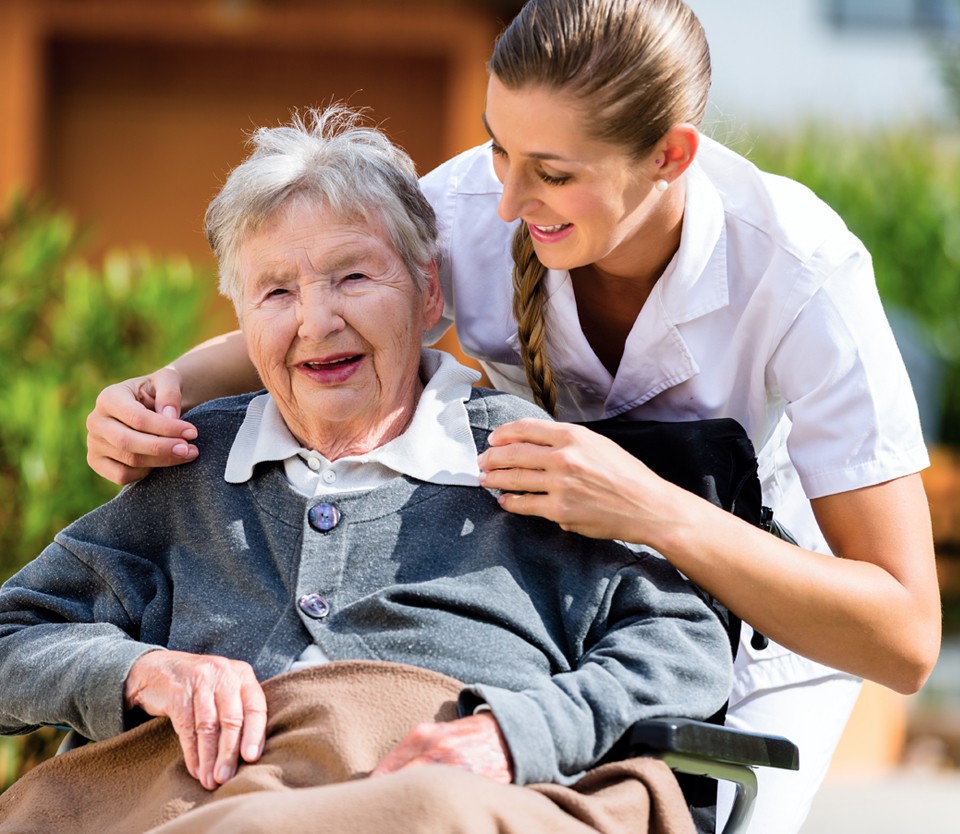 Caregiver comforting elderly woman in wheelchair.
