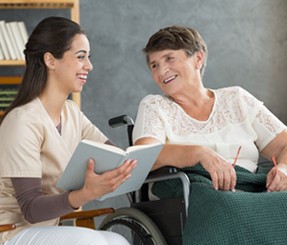 Client and caregiver enjoy each other's company as they read a book together.