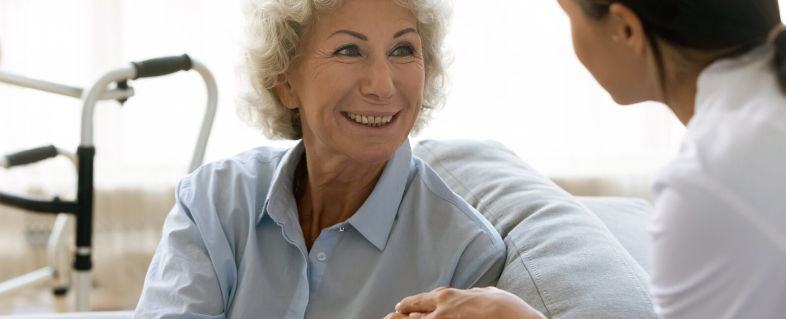 Senior woman looks back at her caregiver while smiling at her.