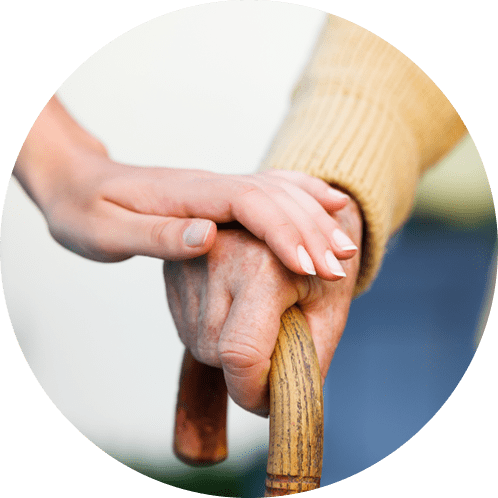 Close up of elderly hand on cane and caregiver’s hand on top.