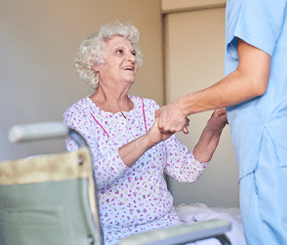 Male Health Care Worker Holds Hands with Smiling Elderly Woman