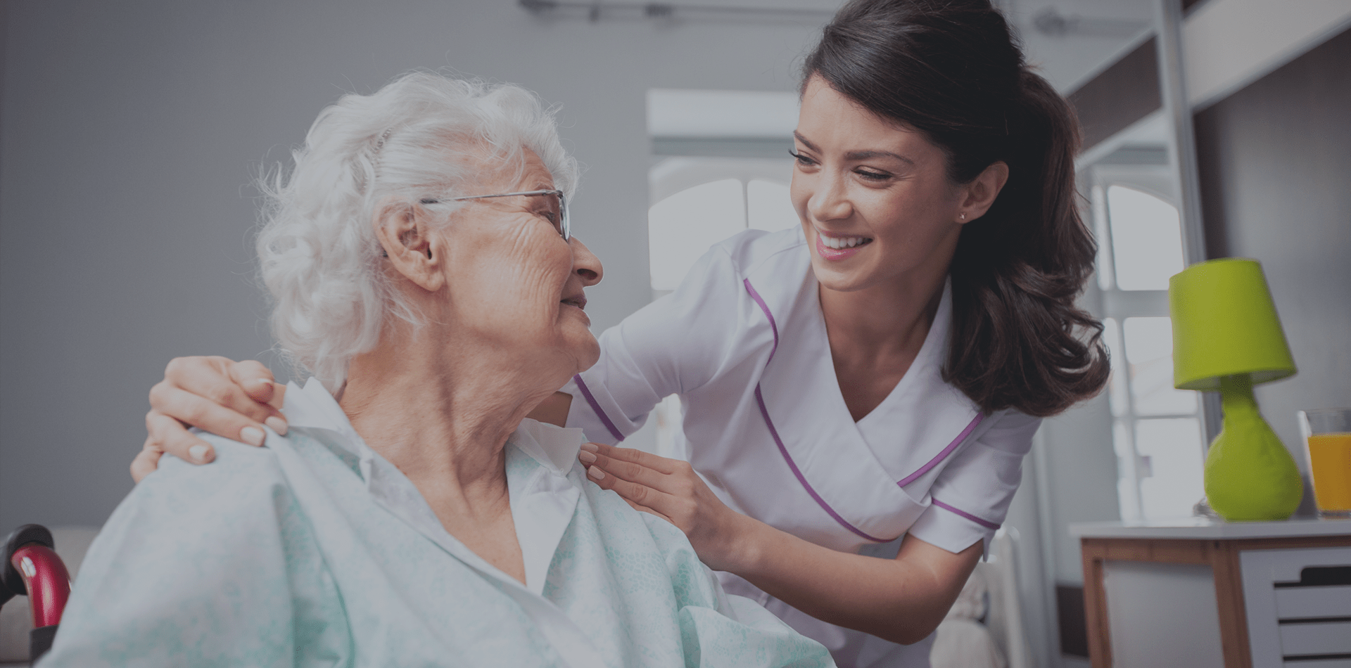 Home Care Aid Smiling at Sitting Senior Woman