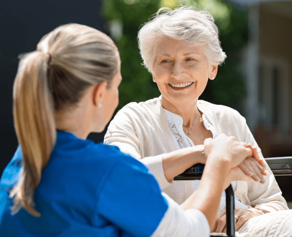 Home Care Professional Holding Hands with Elderly Woman in a Wheelchair