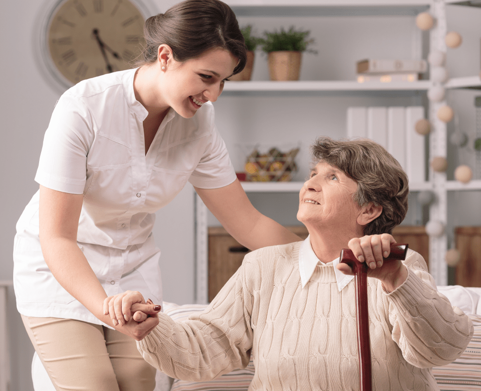 Health Care Worker Helps Senior Woman With Walking Stick