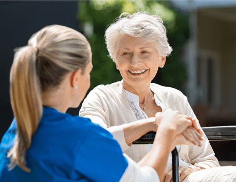 Home Care Nurse Holding Hands With Elderly Woman