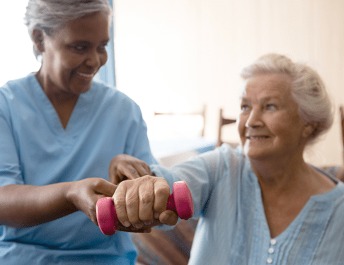 Elderly Woman Lifting Weight With Home Care Helper