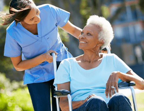 Home Care Helper Aids Elderly Woman in a Wheelchair