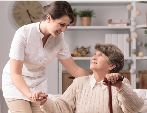 Home Care Helper Aids Woman Sitting Down With a Walking Stick
