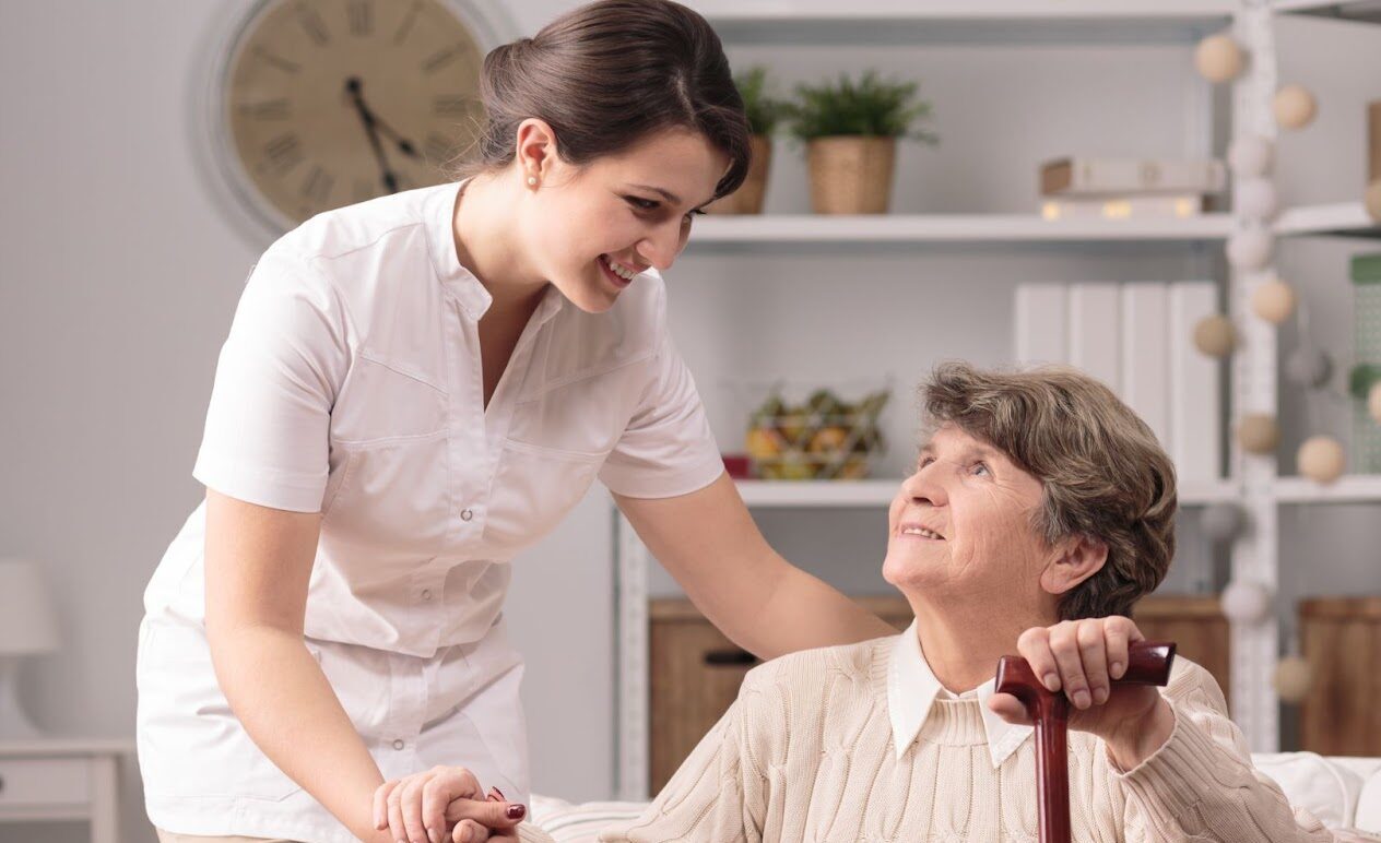 Caregiver helps elderly woman after surgical procedure.